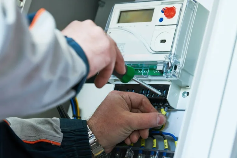 Elektrikář vyměňuje elektroměr v rozvaděči pomocí šroubováku.