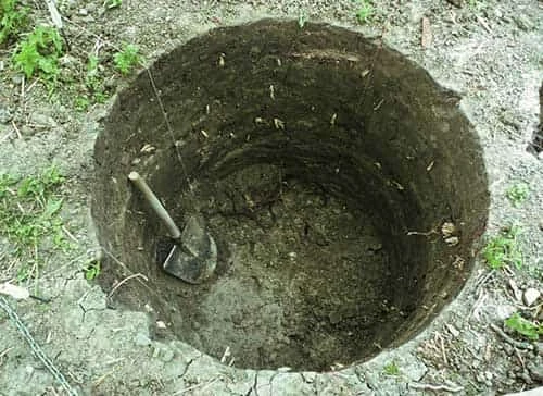 Vykopaná studna s lopatou uvnitř jako příklad kontaminované vody.