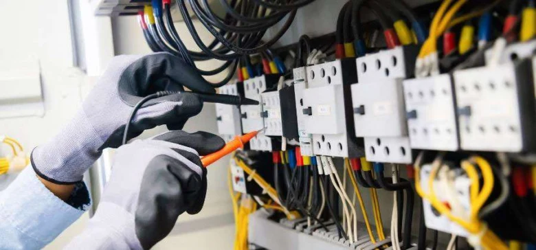 Elektrikář měří proud v rozvaděči s jističem.