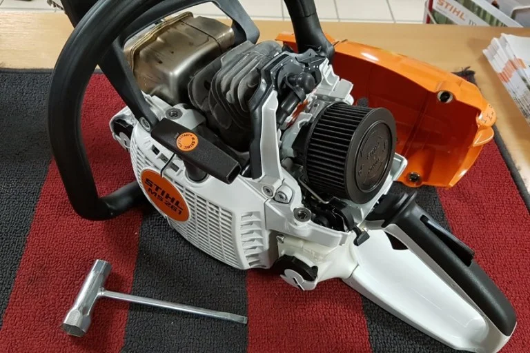 Rozbitá motorová pila s odhaleným motorem pro diagnostiku.