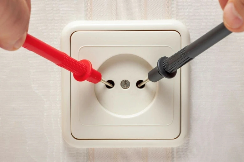 Testování elektrické zásuvky pomocí měřicího přístroje.