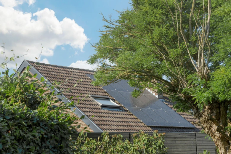 Fotografie střechy domu s fotovoltaickými panely pro výrobu elektřiny.