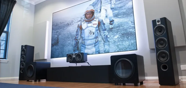 Domácí kino s velkým televizorem a černým subwooferem v obývacím pokoji.