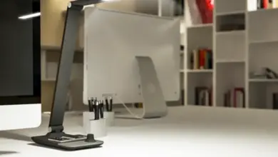 Moderní stolní lampa na bílém pracovním stole v kanceláři.
