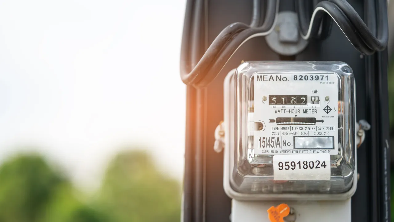 Blízký záběr na elektroměr připojený k elektrické síti venku.