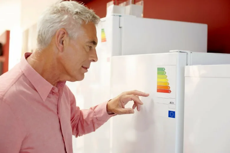 Muž kontroluje energetickou třídu lednice v obchodě.