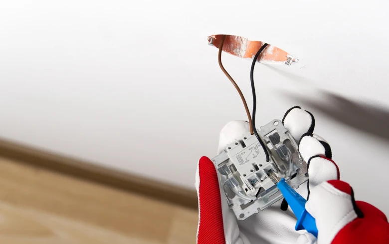 Ruční instalace elektrického zásuvky s připojením vodičů do zdi.