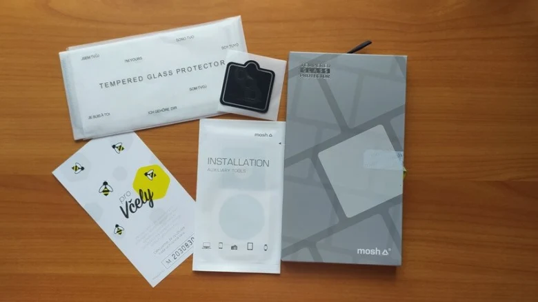 Sada ochranného skla pro telefon s příslušenstvím na dřevěném povrchu.