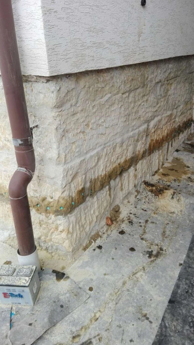 Brownská hydroizolační hmota aplikovaná na kamenný základ s vodou.