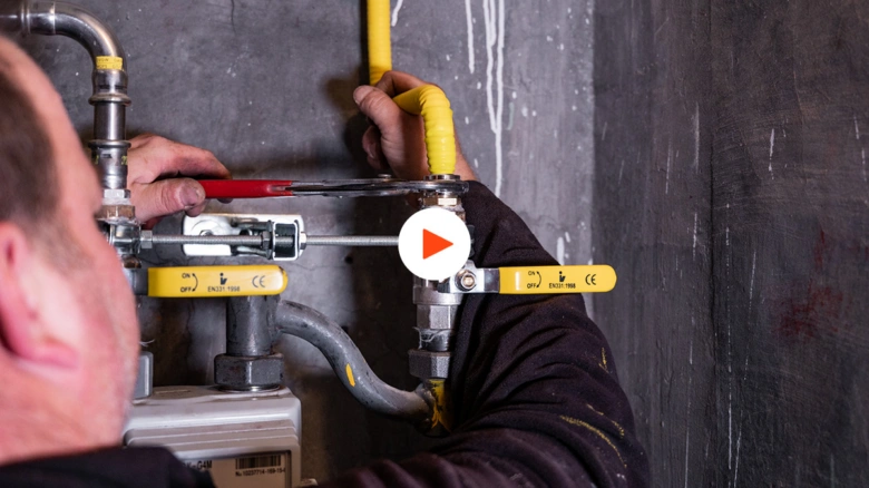 Technik opravuje žlutě označené plynové potrubí v domovní instalaci.