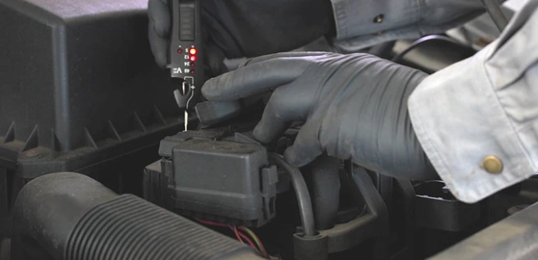 Technik měří zapalovací cívku multimetrem v motoru.