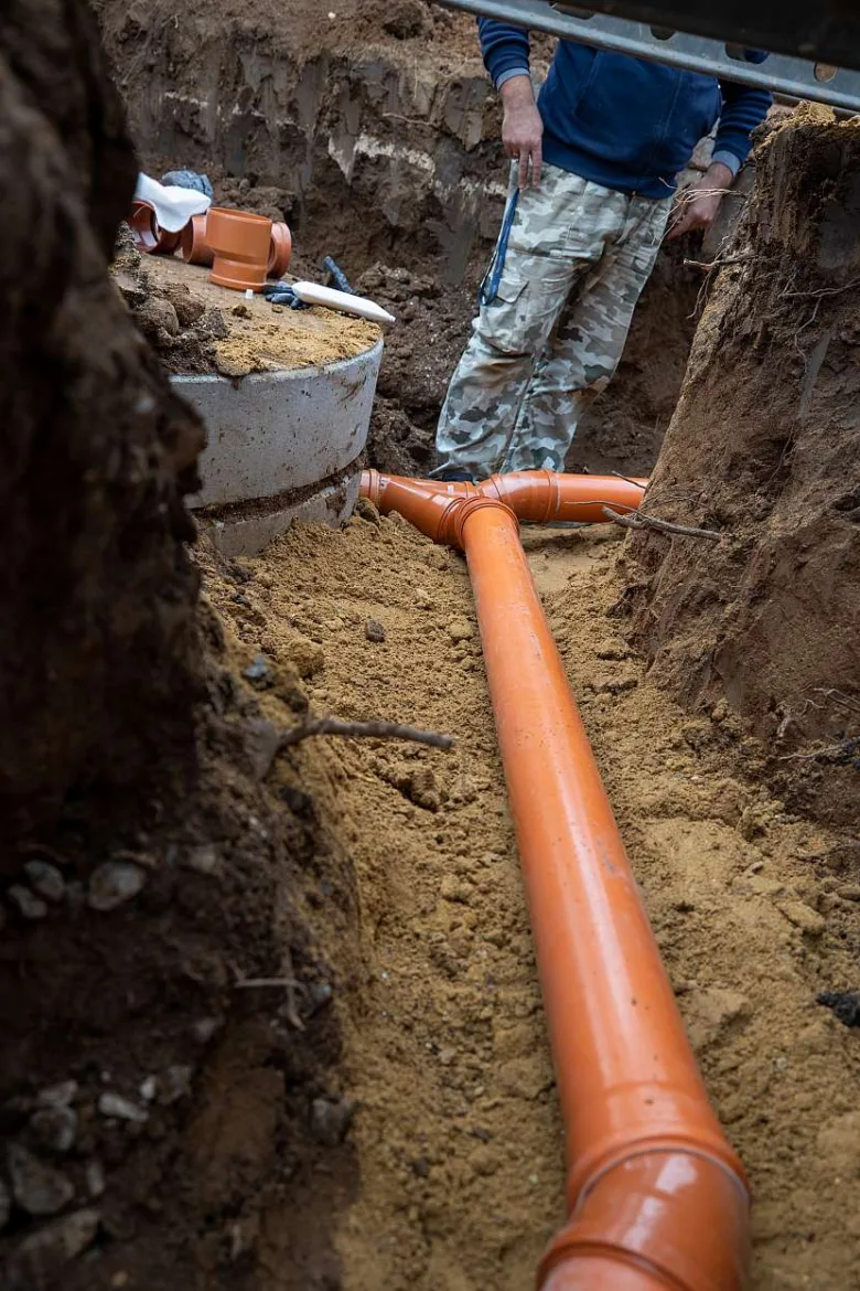 Instalace oranžové dešťové kanalizační trubky v zemi.