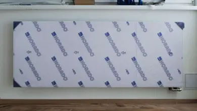 Nový bimetalický radiátor s ochrannou fólií na zdi.