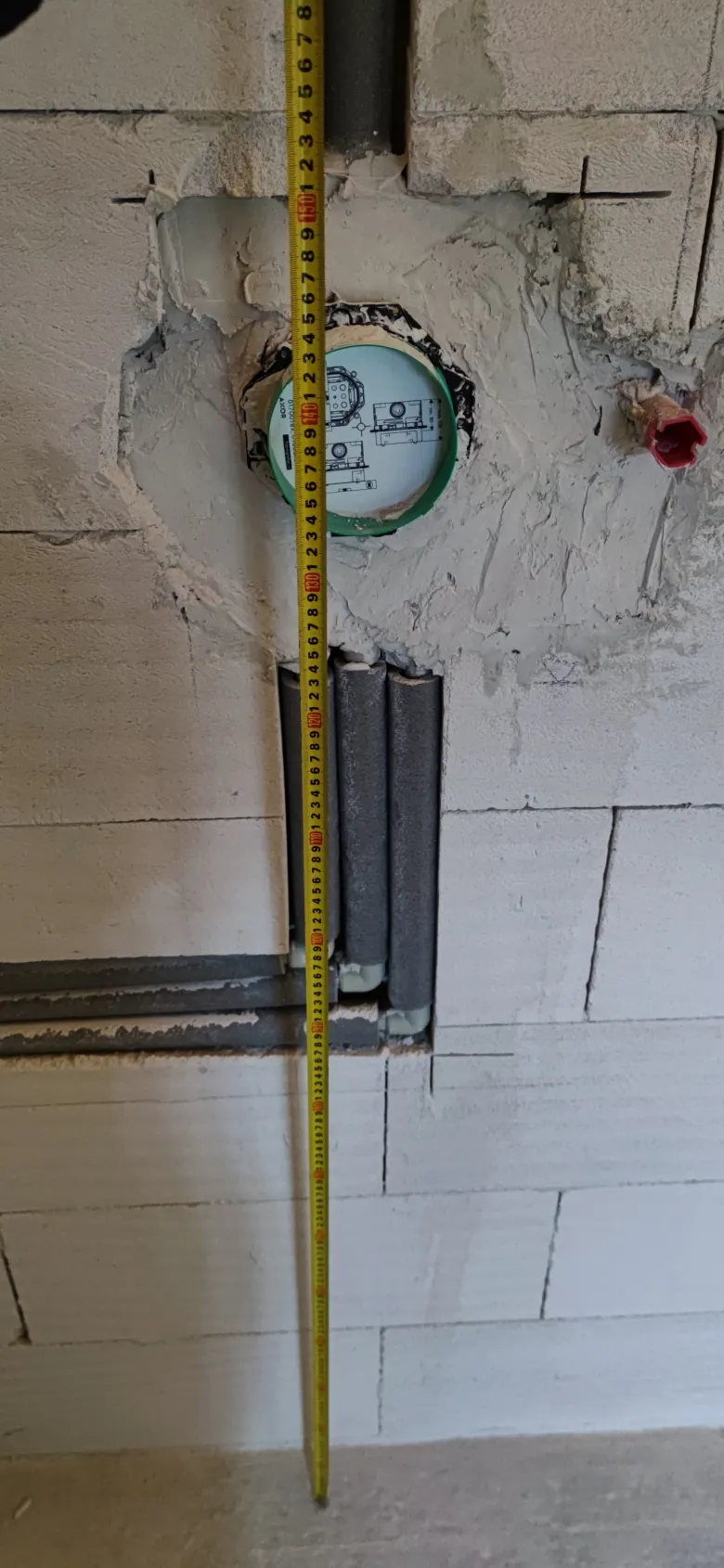 Instalace vodovodního potrubí do zdi s měřicí páskou pro DIY