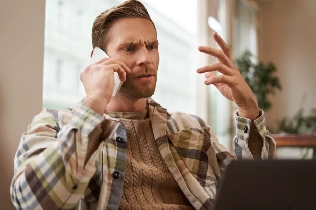 Muž mluví na telefonu a gestikuluje při vysvětlování.