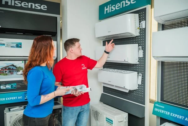 Muž ukazuje na klimatizaci v obchodě s elektronikou.
