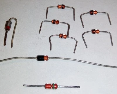 Různé typy elektronických součástek: diody a rezistory na bílém pozadí.