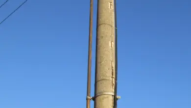 Konkrétní elektrický sloup s vedením na pozadí modré oblohy.
