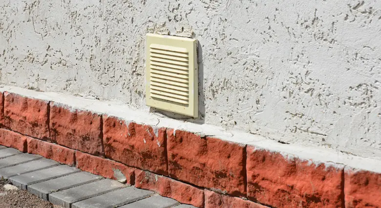 Žlutý větrací otvor na vnější zdi garáže.