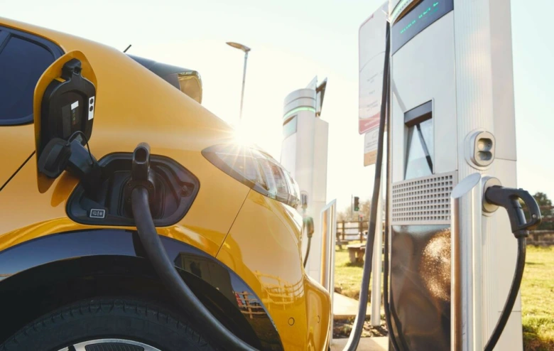 Žlutý elektromobil nabíjen na veřejné stanici pro elektrická vozidla.
