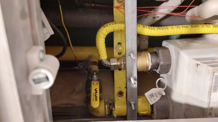 Žluté plynové potrubí s ventily uvnitř skříňky.