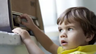 Dětské ruce otáčejí knoflík na starém rádiu.