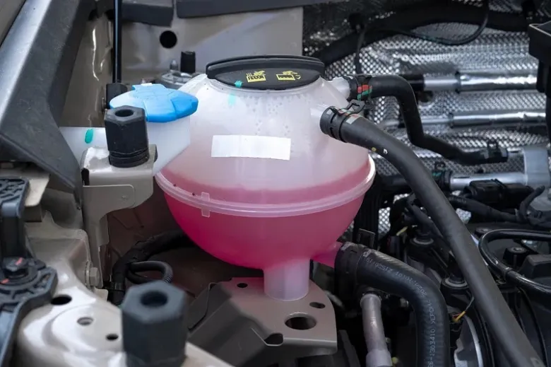 Prozředěná nádrž s růžovým chladicím prostředkem v motorovém prostoru.
