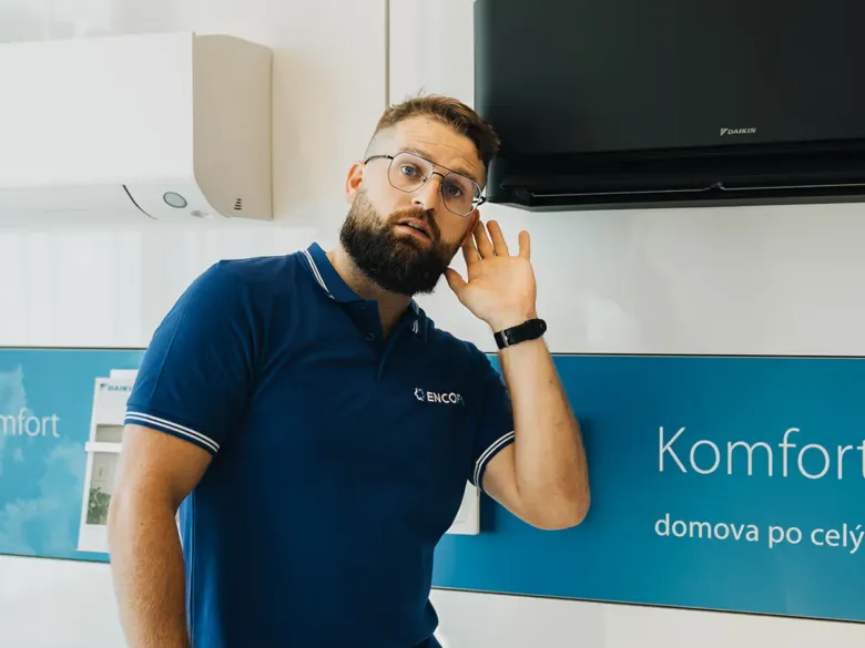 Muž stojí vedle klimatizace v interiéru.