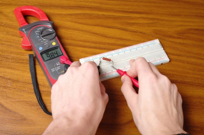 Ruční měření elektrického obvodu pomocí multimetru na plošném spoji.