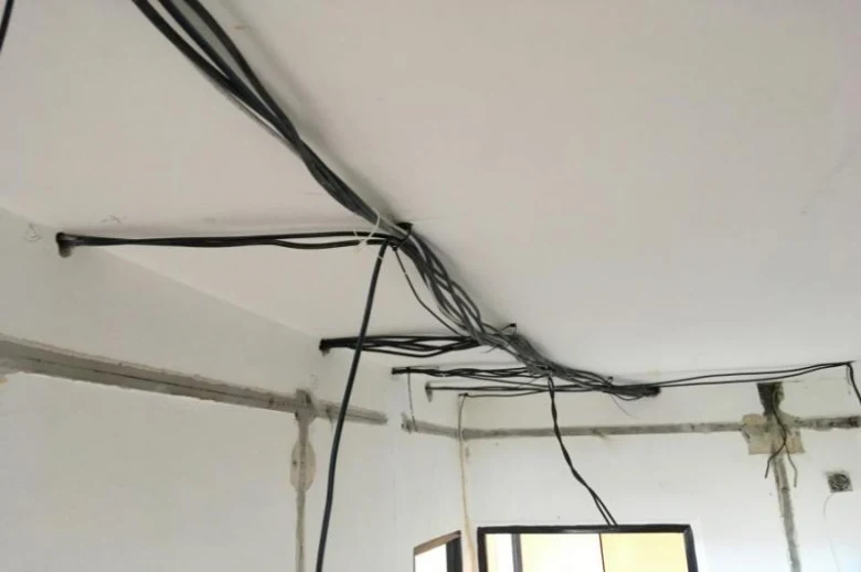 Zamotané staré elektrické kabely na stropě v bytě.