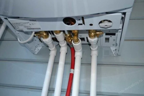 Připojení plynového kotle s bílými hadicemi a červenou trubicí.
