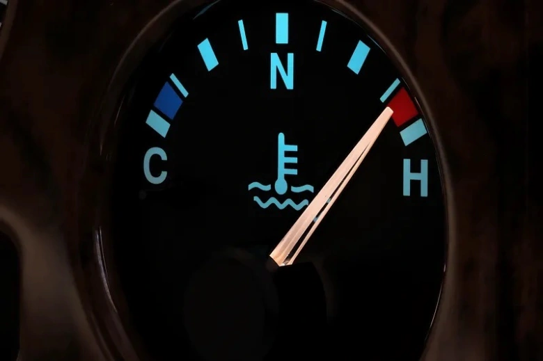 Červený ukazatel teploměru motoru ukazuje na horko.