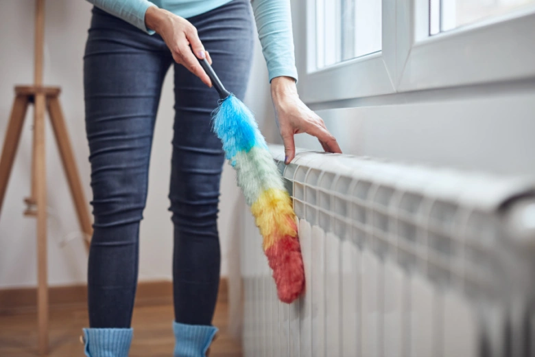 Žena čistí radiátor od vzduchu pomocí barevného štětce.