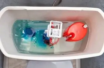 Vnitřní součásti záchodové nádrže ponořená v barvené vodě.