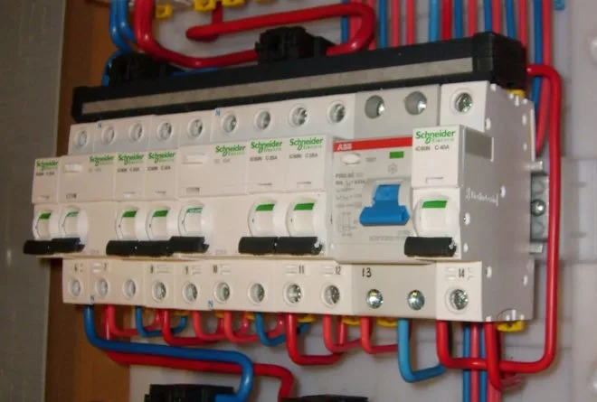 Elektrická rozvaděč s přepínači a červenými modrými vodiči pro instalaci.