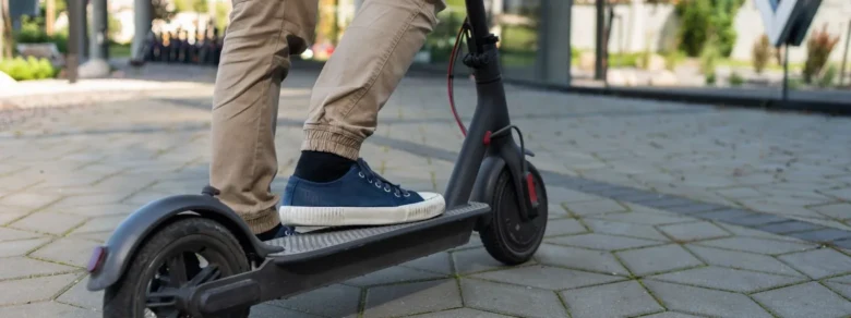 Člověk stojí na elektrické koloběžce v městském prostředí.