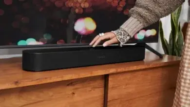 Ruka nastavuje zvukový systém pod televizorem pro lepší audio.