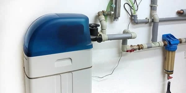 Domácí změkčovač vody připojený k vodovodním potrubím.