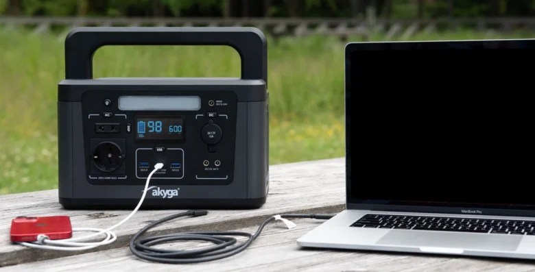 Mobilní zdroj energie nabíjí notebook přes kabel USB-C venku.