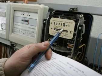 Ruka s tužkou ukazuje na elektrický měřič v instalační skříni.