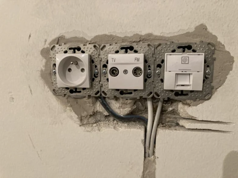 Nevyhotovená elektrická zásuvka s moduly pro síť, televizi a internet.
