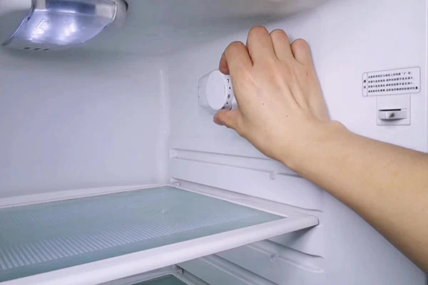 Ruka nastavuje teplotu v prázdné chladničce.