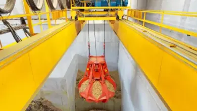 Oranžový kbelík na dřevo pelety nad betonovou nádrží.