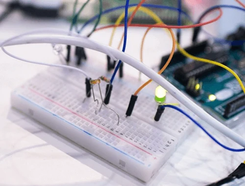 Breadboard s Arduino a zelenou diodou ukazuje elektronický obvod.