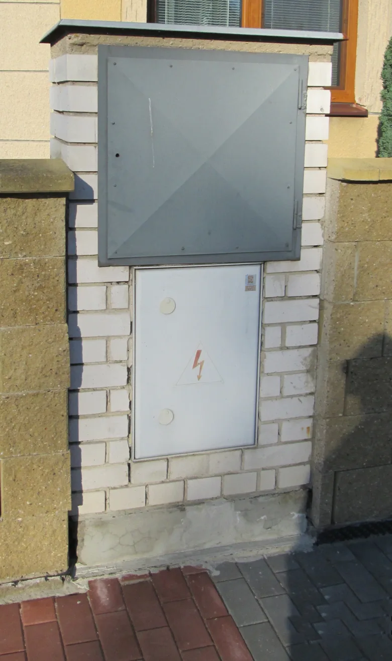 Elektrická skříň na zdi obytné budovy s varováním vysokého napětí.