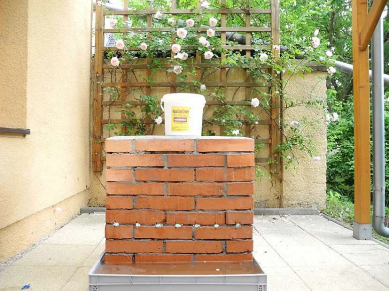 Kamená zeď s nádobou na aplikaci voděodolného nátěru