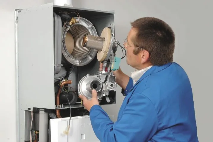 Technik čistí vnitřní části plynového kotle s ohřívačem tepla.