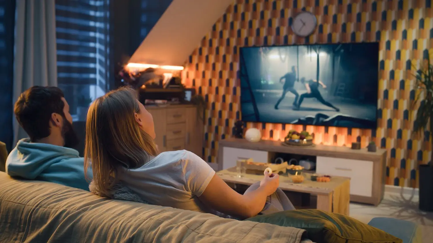 Manželé sledují digitální televizi v obývacím pokoji.
