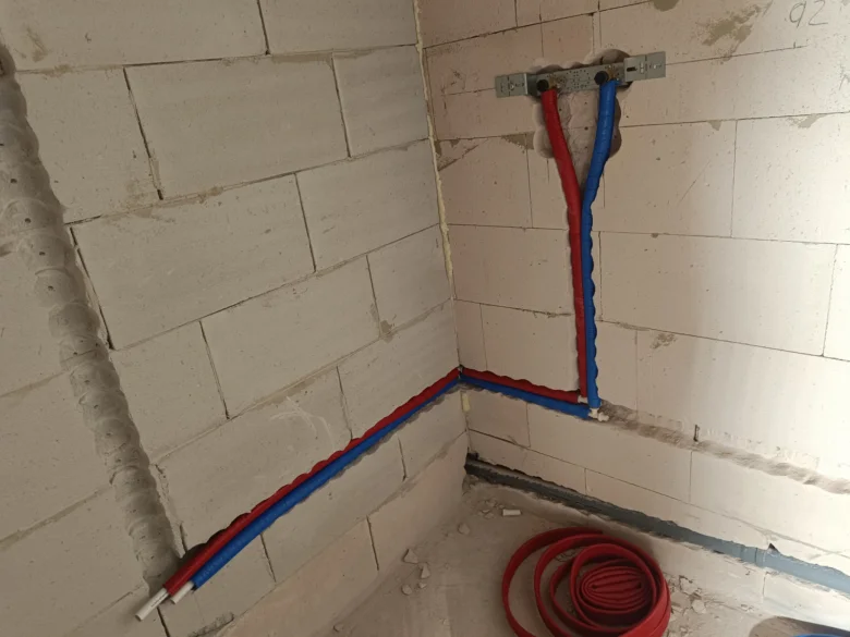 Instalace vodovodních trubek v rohu zdiva pro domácí rozvod vody.