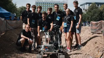 Tým s elektromobilovým vozítkem na testovacím terénu.